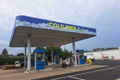 A gas station canopy wrapped with custom Vinyl that reads Cold Beer