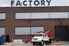 Channel letters being installed on a building reading Factory
